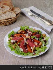 Salad of grapefruit and persimmon in lettuce leaves with cashews, almonds, pomegranate