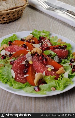 Salad of grapefruit and persimmon in lettuce leaves with cashews, almonds, pomegranate