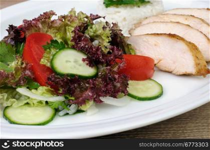 salad of lettuce, cucumber and tomato with slices of chicken breast