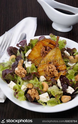 Salad of lettuce with walnuts, cashews, slices feta, halves of caramelized pear