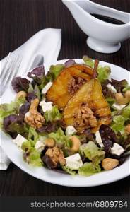 Salad of lettuce with walnuts, cashews, slices feta, halves of caramelized pear