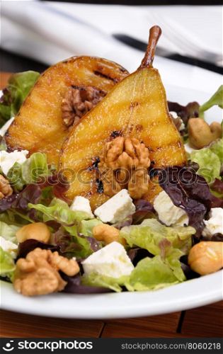 Salad of lettuce with walnuts, cashews, slices feta, halves of caramelized pear