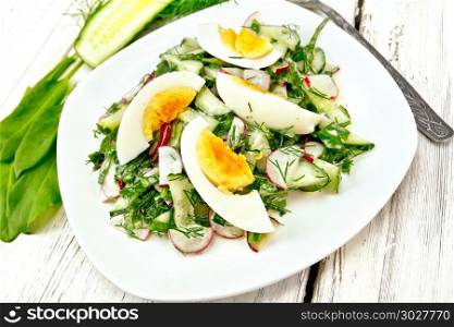 Salad of radishes, cucumber, sorrel, greens and eggs, dressed with mayonnaise and sour cream in a white plate on the background of wooden board. Salad with radish and egg in plate on board