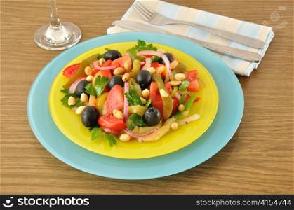 Salad of roasted peppers with tomato, peanuts and olives, onions and greens