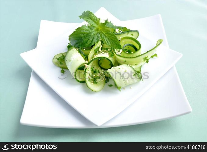 Salad of sliced green cucumbers with herbs and sesame seeds with mint leaves