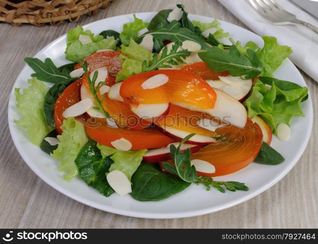 salad of spinach, arugula, lettuce, persimmon, apple and almonds