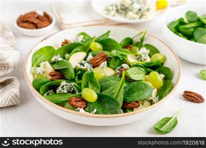 Salad of spinach, pear, grape, pecan and gorgonzola cheese with lemon dressing. Healthy food, diet.