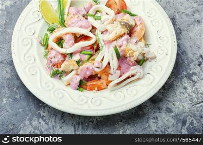 Salad of squid, fish and shrimp on a plate. Appetizing seafood salad.