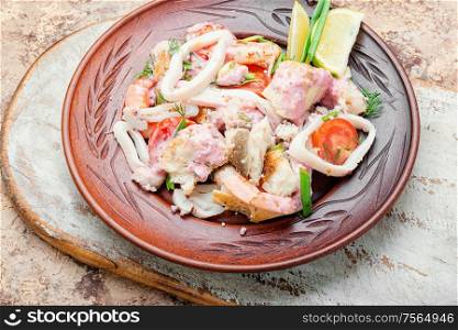 Salad of squid, fish and shrimp on a plate. Delicious spicy seafood salad