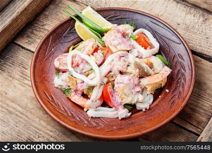 Salad of squid, fish and shrimp on a plate.Homemade seafood salad. Delicious spicy seafood salad