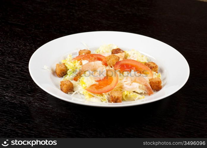 Salad of tiger shrimps, lettuce, chinese cabbage, tomato, garlic rusk, parmesan cheese and sauce