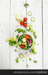 Salad of tomatoes and cucumbers with fresh greens. On a white wooden background.. Salad of tomatoes and cucumbers with fresh greens.