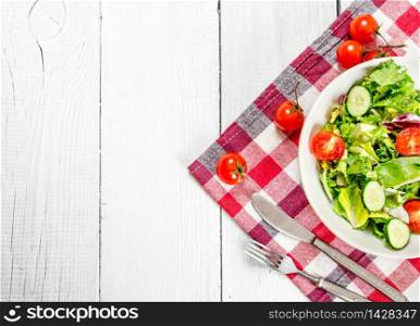 Salad of tomatoes and cucumbers with greens . On a white wooden background.. Salad of tomatoes and cucumbers with greens .