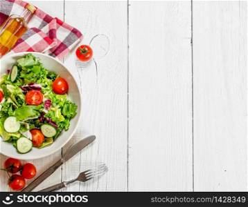 Salad of tomatoes and cucumbers with greens . On a white wooden background.. Salad of tomatoes and cucumbers with greens .