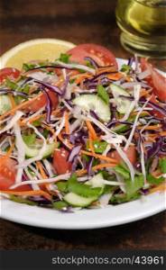 Salad of white and blue chopped cabbage, carrots, cucumber, tomato dressed with oil, lemon, sesame