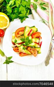 Salad of young zucchini, radish, tomato and mint, flavored with lemon juice and soy sauce in a plate, napkin on a light wooden board on top