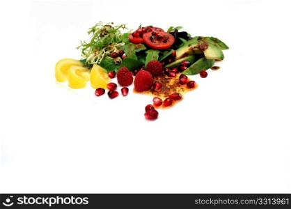 Salad On White. Salad ingredients isolated on a white background with red roma and yellow heirloom tomatoes, avocado slices, spinach leaf, pomegranate seeds, Raspberries topped with Olive oil and Raspberry vinaigrette dressing