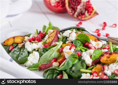 Salad. Spring vegetable salad. Fresh vegetable salad with grilled peach, pomegranate, spinach and fresh cheese.