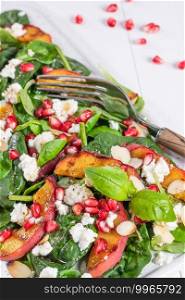 Salad. Spring vegetable salad. Fresh vegetable salad with grilled peach, pomegranate, spinach and fresh cheese.