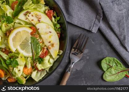 Salad. Spring vegetable salad. Fresh vegetable salad with tomatoes, apple, nuts, seeds and lemon. Olive oil pouring into bowl of salad
