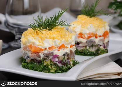 salad stacked chopped herring with potatoes, carrots, onions, egg with mayonnaise strewn with grated egg yolk