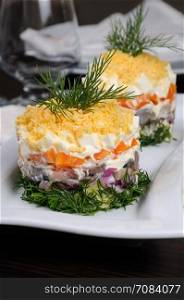 salad stacked chopped herring with potatoes, carrots, onions, egg with mayonnaise strewn with grated egg yolk
