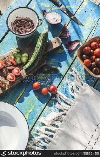 Salad with arugula, Little Gem, cheese, olives, tomatoes, cucumber, onion and caramelized nuts. Concept for healthy food and diet. Natural lighting. Blue wooden vintage table.