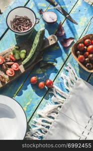 Salad with arugula, Little Gem, cheese, olives, tomatoes, cucumber, onion and caramelized nuts. Concept for healthy food and diet. Natural lighting. Blue wooden vintage table.