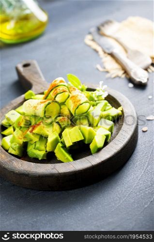 Salad with , avocado, cucumber and nuts on plate, top view