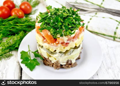 Salad with beef, boiled potatoes, pickles, cheese, tomato, parsley in the plate, napkin, background dill on a wooden board