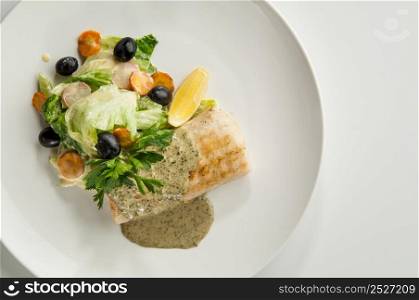 salad with black olives in a round plate on a white background. salad in a white plate
