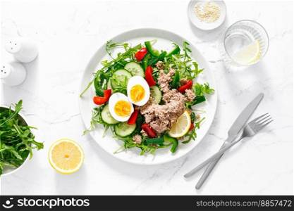 Salad with canned tuna, boiled egg, arugula and fresh vegetables. Top view