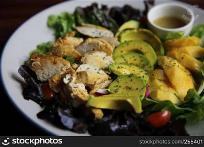 Salad with Chicken avocado and mango on wood background