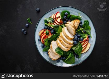 Salad with chicken meat. Fresh fruit salad with chicken breast. Meat salad with chicken fillet, spinach, apples and blueberry on plate, top view