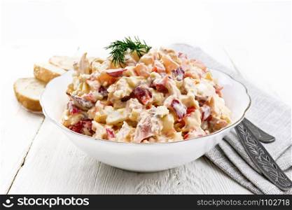 Salad with chicken, sweet pepper, tomato, egg and cheese seasoned with mayonnaise and garlic in a dish, towel, bread and forks on a wooden board background