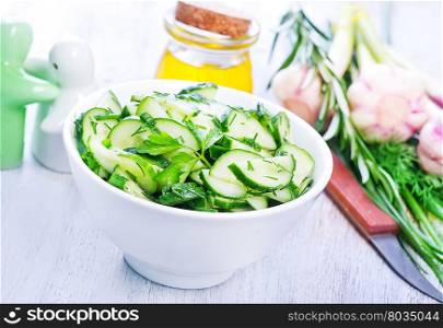 salad with cucumber in the white bowl and on a table
