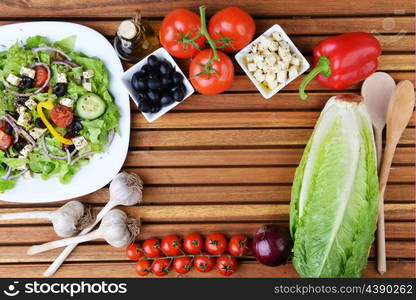 salad with feta cheese and fresh vegetables on wooden background