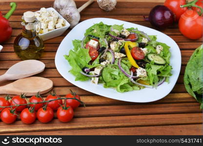 salad with feta cheese and fresh vegetables on wooden background