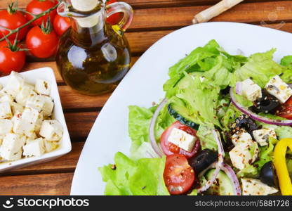 salad with feta cheese and fresh vegetables on wooden background