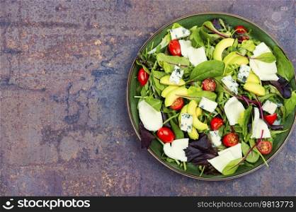 Salad with fresh lettuce, greens, avocado, tomatoes and cheeses. Space for text.. Vegetable salad with greens and mozzarella