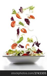 salad with fresh vegetables falling on plate, mediterranean cuisine
