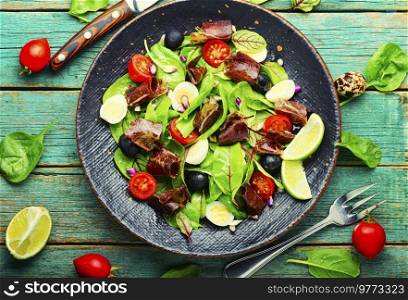 Salad with greens, tomato, egg, lime slices of meat. Homemade salad on wooden table. Spring raw salad with meat, top view