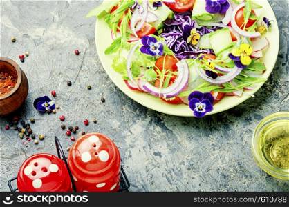 Salad with greens, tomatoes, cabbage, onions and edible flowers.Healthy vegetable salad. Salad with vegetables and herbs