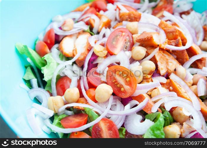 Salad with grilled chicken, cherry tomatoes, corn salad, chick peas, fresh lettuce and onion. Home made food. Concept for a tasty and healthy meal. Top view. Close up.