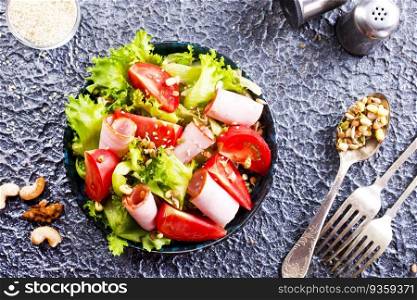 salad with ham and tomato on black plate