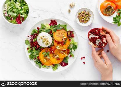 Salad with persimmon, burrata, pomegranate and pistachio, healthy food, top view
