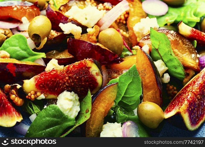 Salad with plums,figs,olives and feta cheese.Autumn salad of fruits and green.Close up. Autumn salad with fruit and green