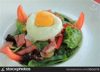 Salad with poached egg, paprika and bacon