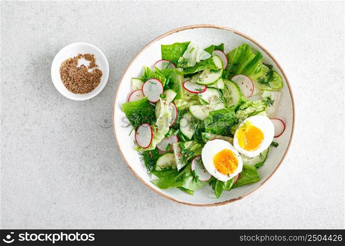 Salad with radish, cucumber, romaine lettuce and soft boiled egg, top view