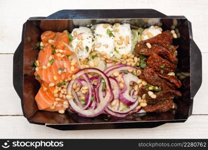 Salad with salmon for delivery on a wooden table